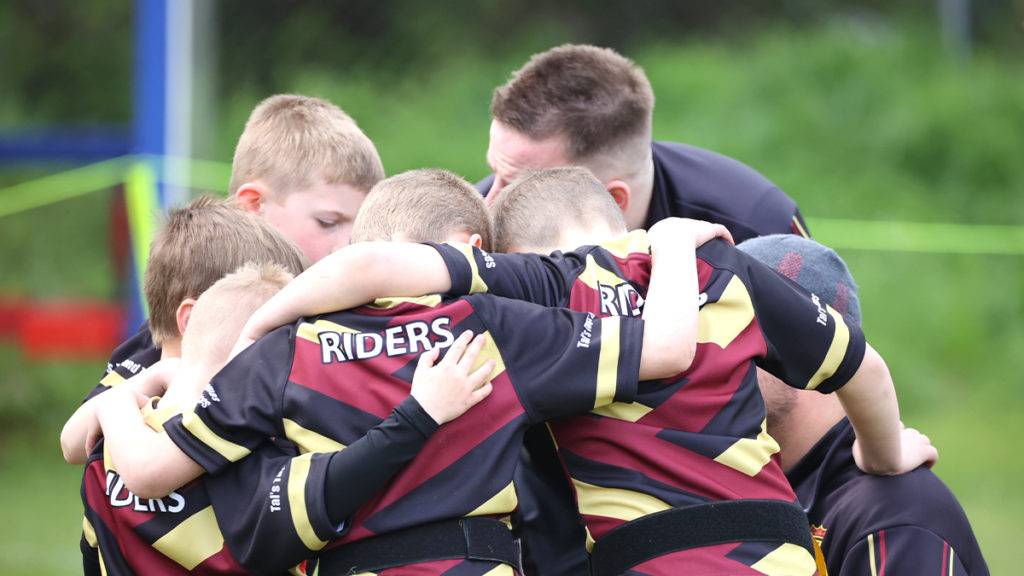 A rugby team huddles around their coach