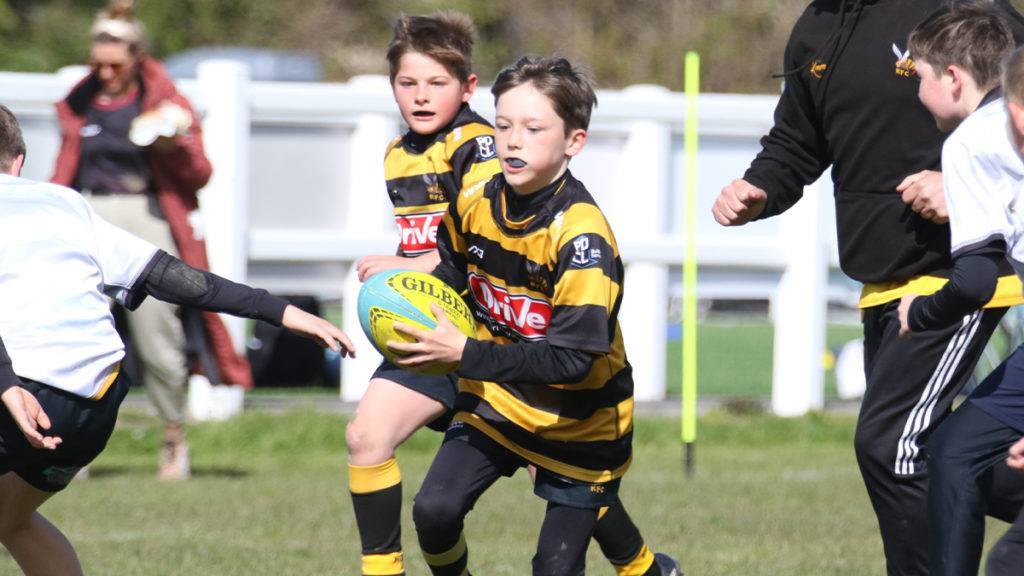 A rugby player, with gum guard showing, weaves between opposing players