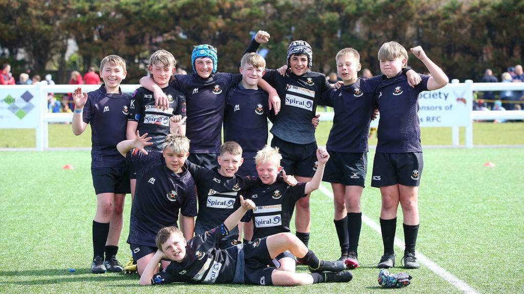 A boys rugby team pose and cheer