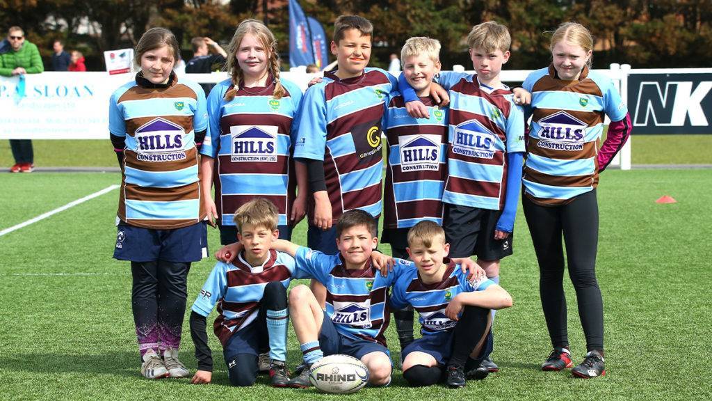 A mixed rugby team of boys and girls pose