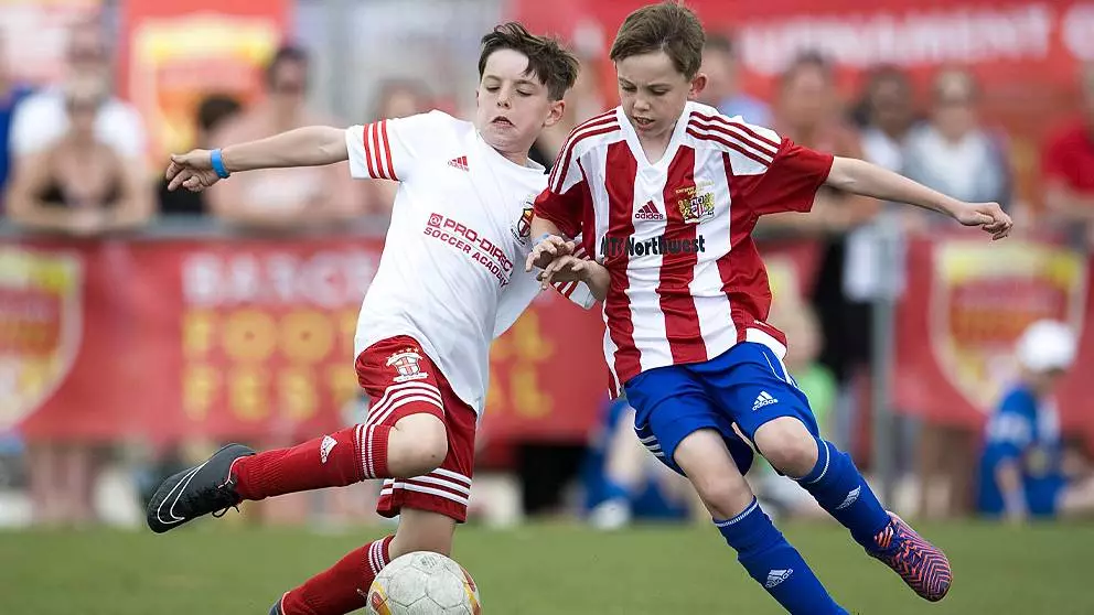 Two opposing junior boy footballers compete for the ball at the Costa Daurada Football Cup.