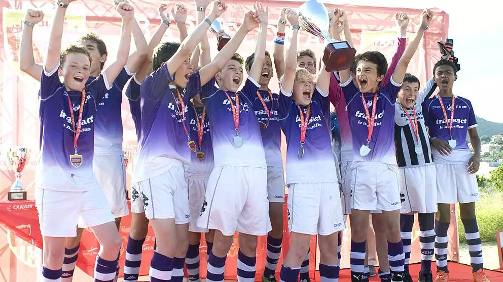 Teenage boys team celebrating listing the trophy at the Barcelona Football Festival.