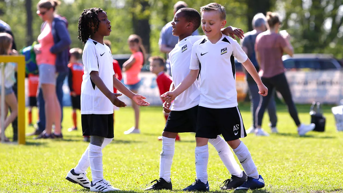 Easter Open Football with three young boy footballers congratulating each other.