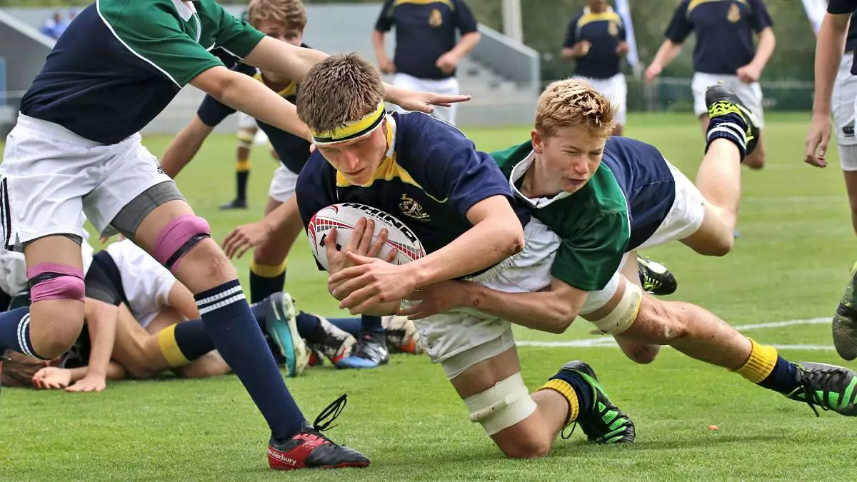 Older boys tackle each other competing for the rugby ball.