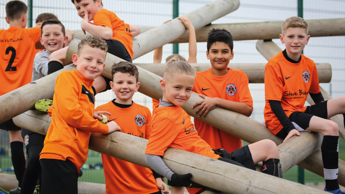 7 boys from the same team pose on a wooden climbing frame