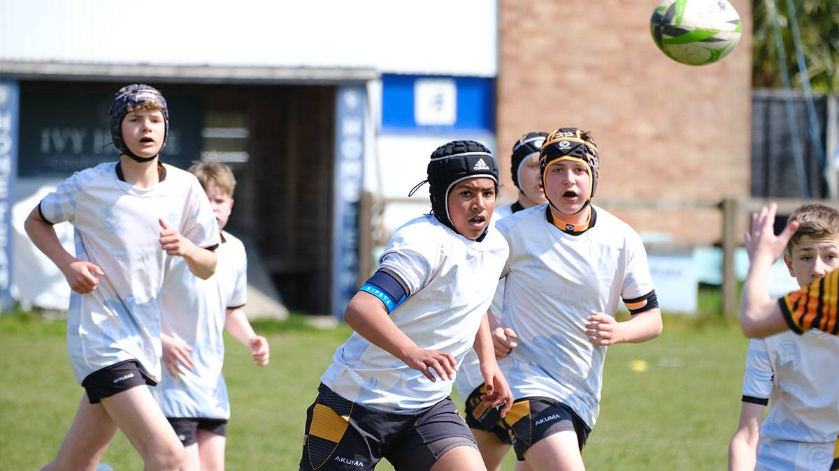 Teenage boy rugby players chase the ball.
