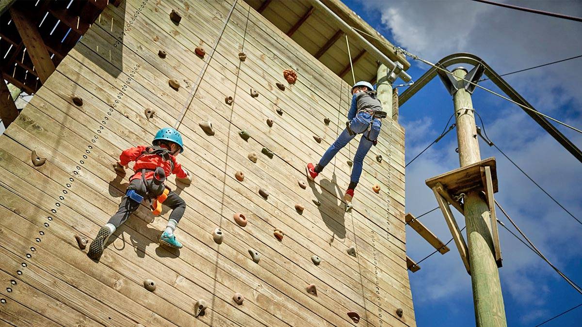 Two children take part in a climbing wall activity at a PGL venue