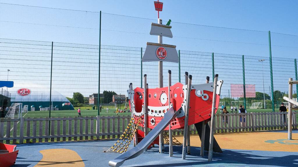 Kids playground in the foreground with children playing on Poolfoot Farm facilities in the background
