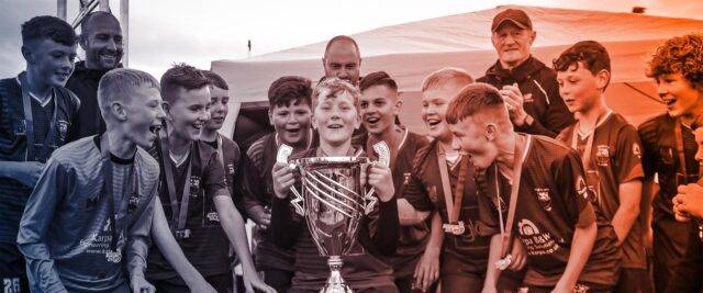 Children's football team lift a trophy