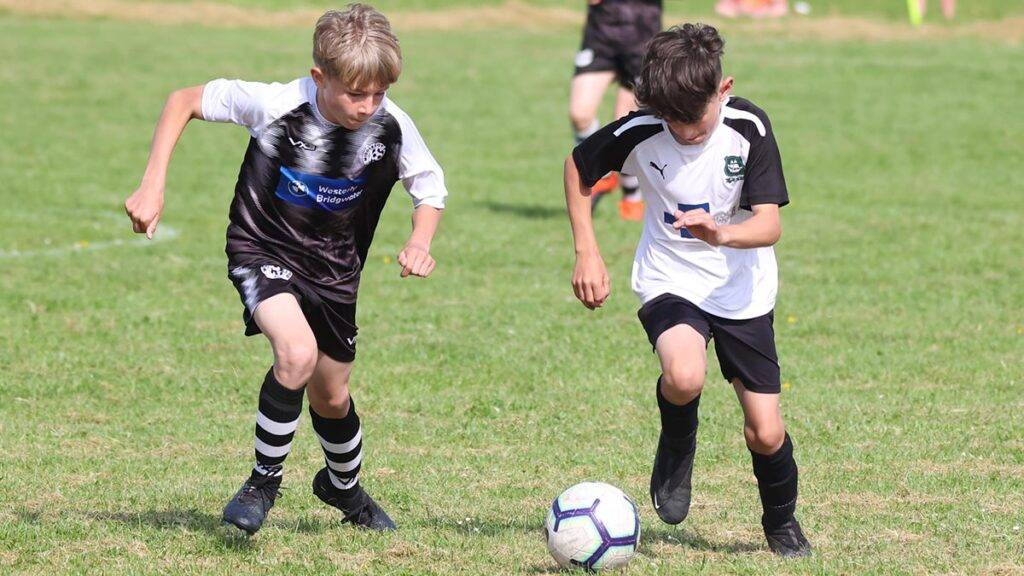 Two players from different sides run for the football