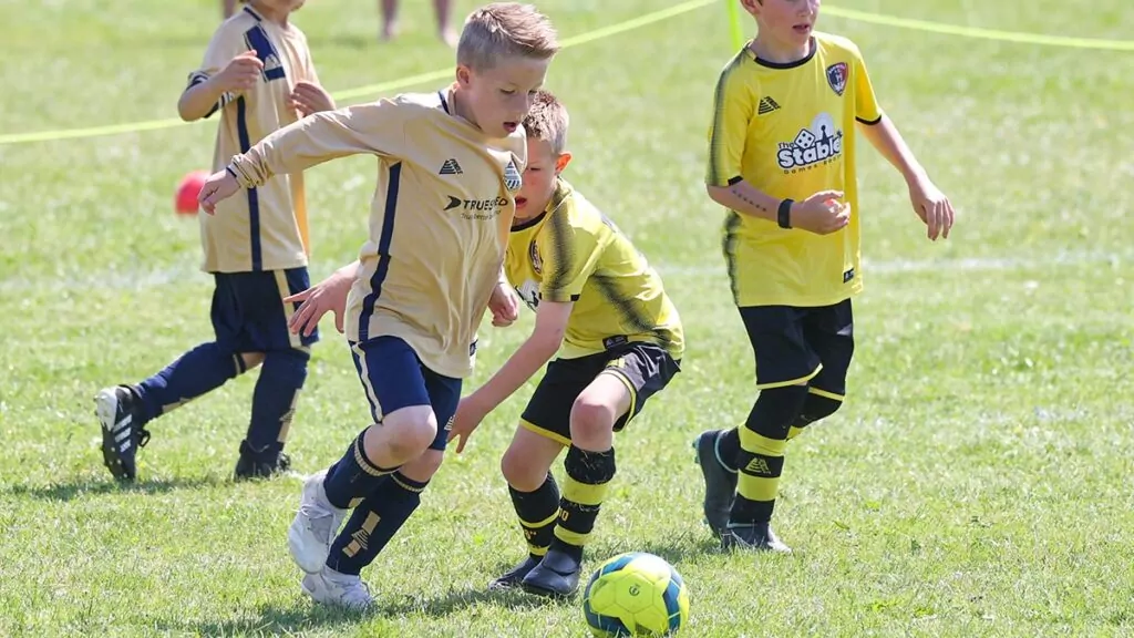 A football player dribbles past an opponent whilst team mates look on