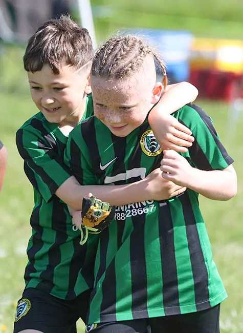 Football players from same side smile and hug