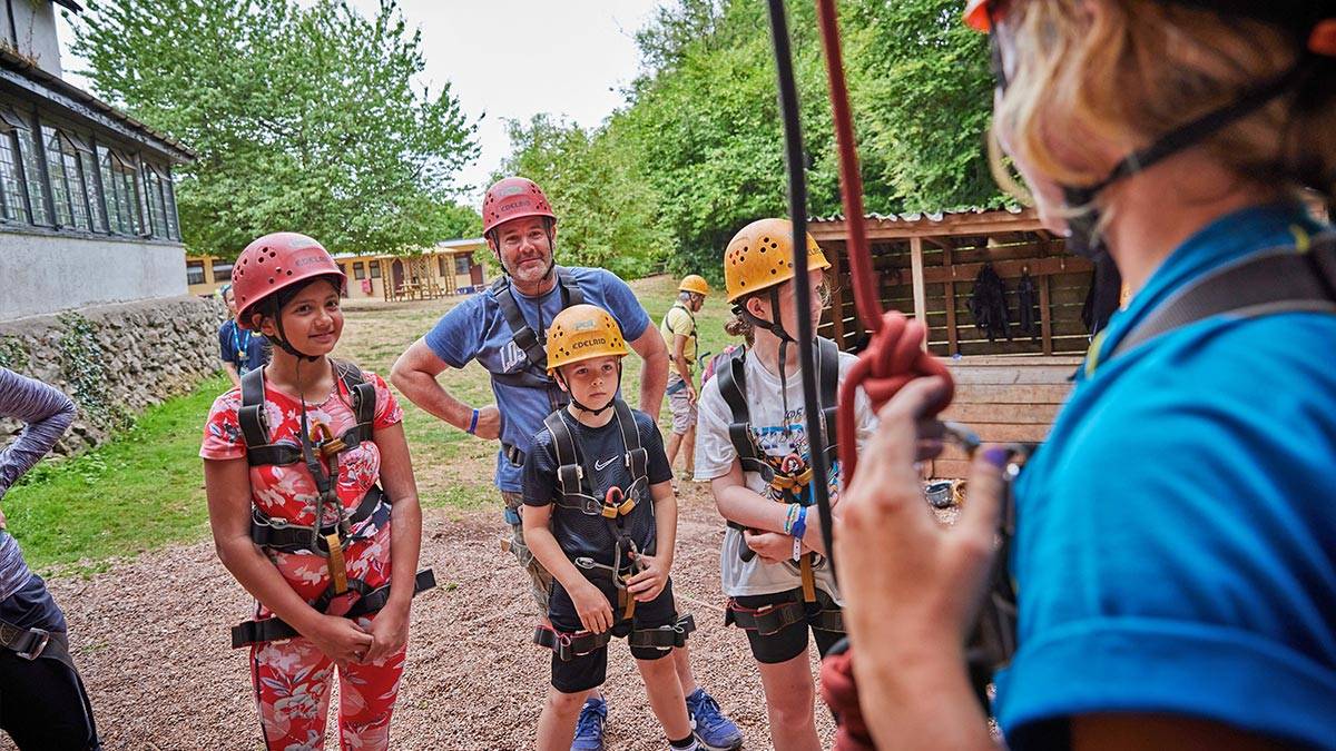 Three children and an adult listen to a instructor before taking part in an activity 