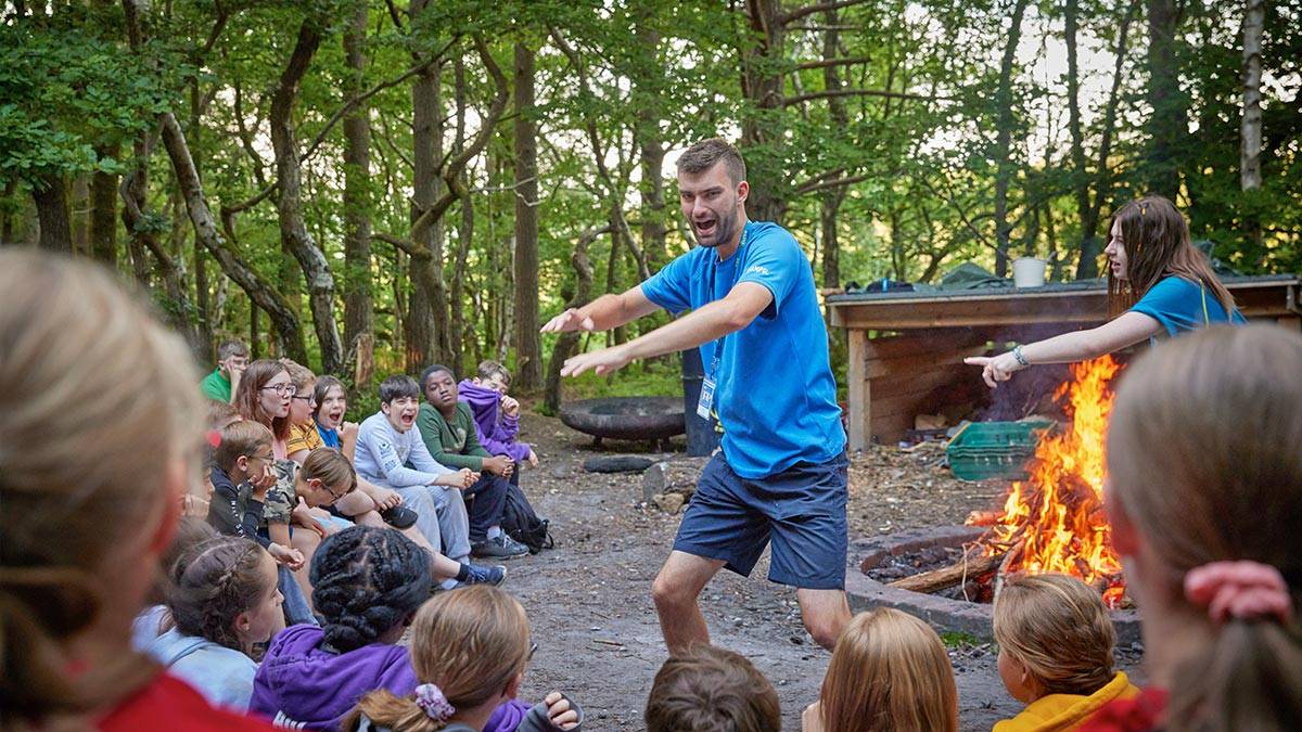 Man tells a story around a campfire to a group of kids