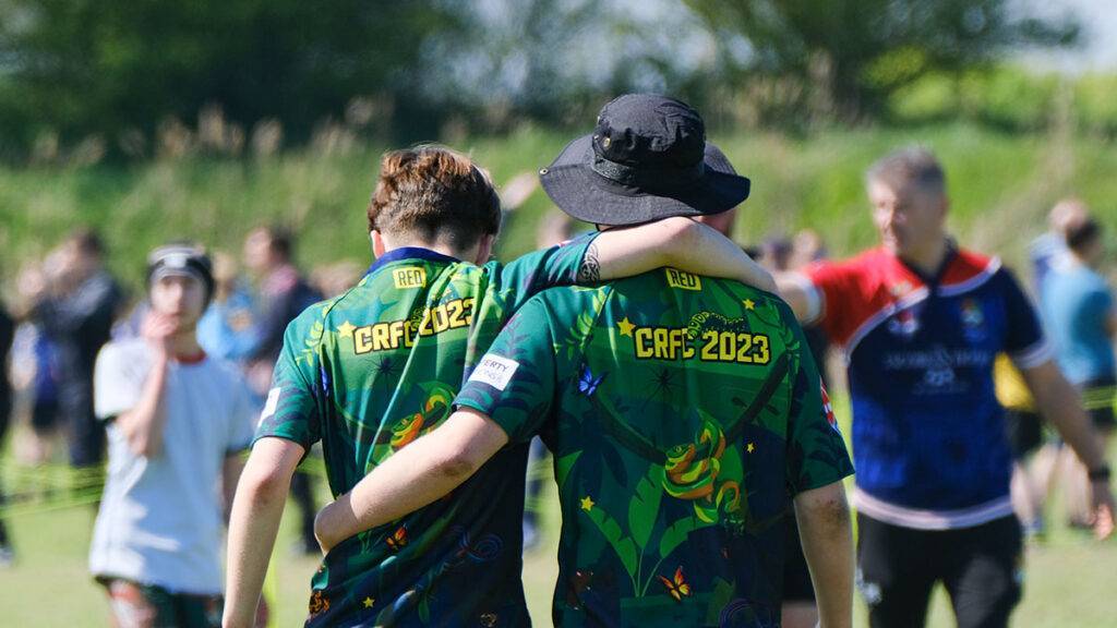 Two rugby players walk off the pitch with arms around each others back