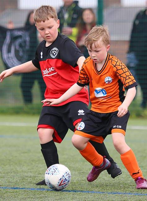 Two children football players compete for the ball