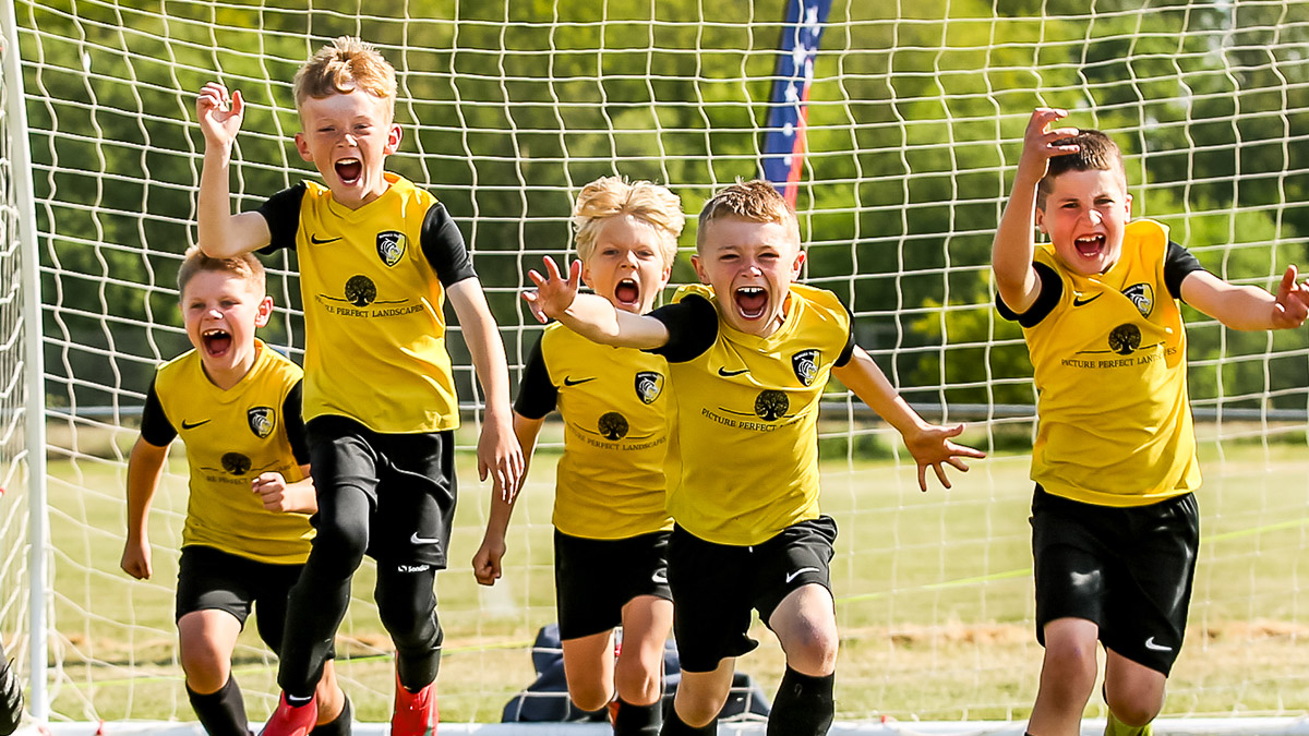 A young team of footballers running towards the camera having fun