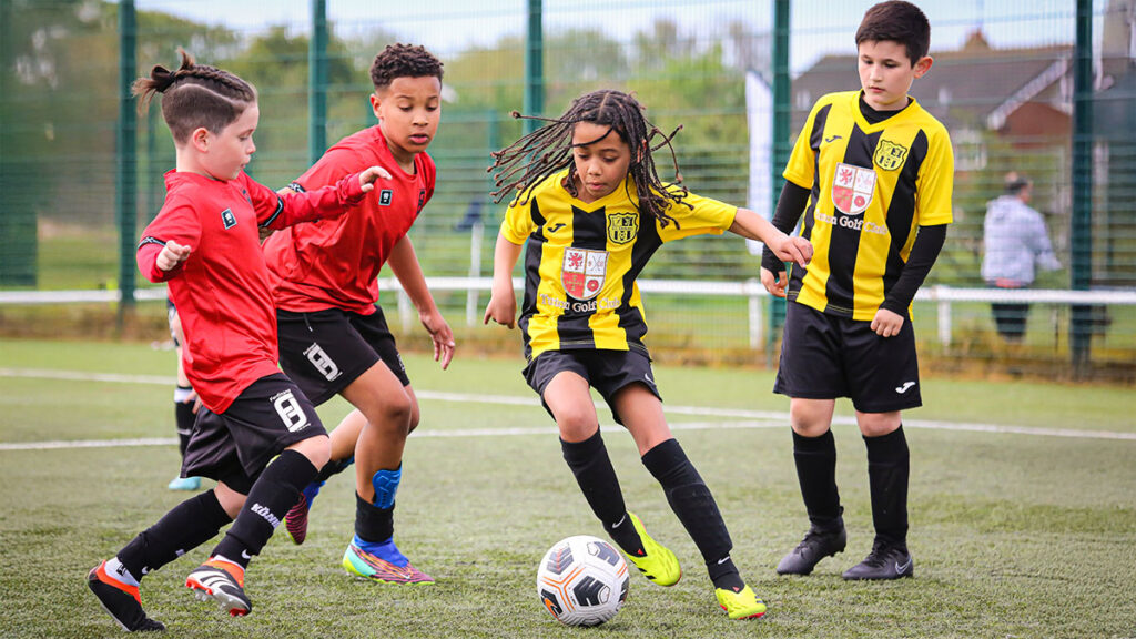 Two youth football teams challenging each other for the football