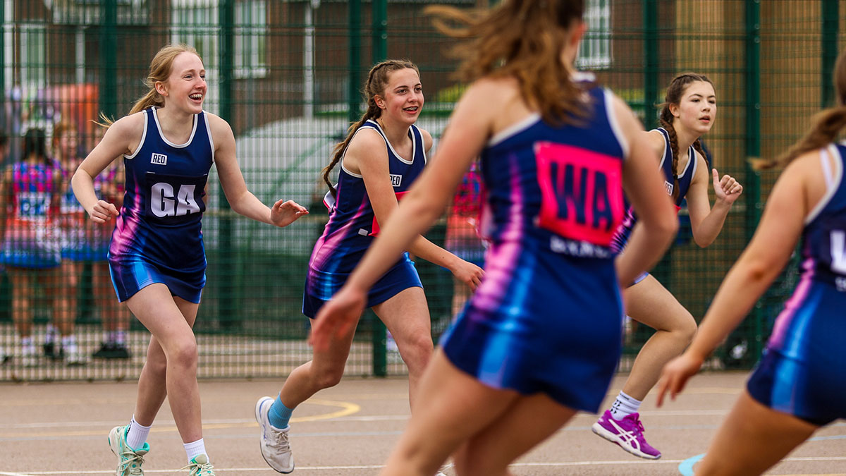 A young netball team running in celebration after scoring