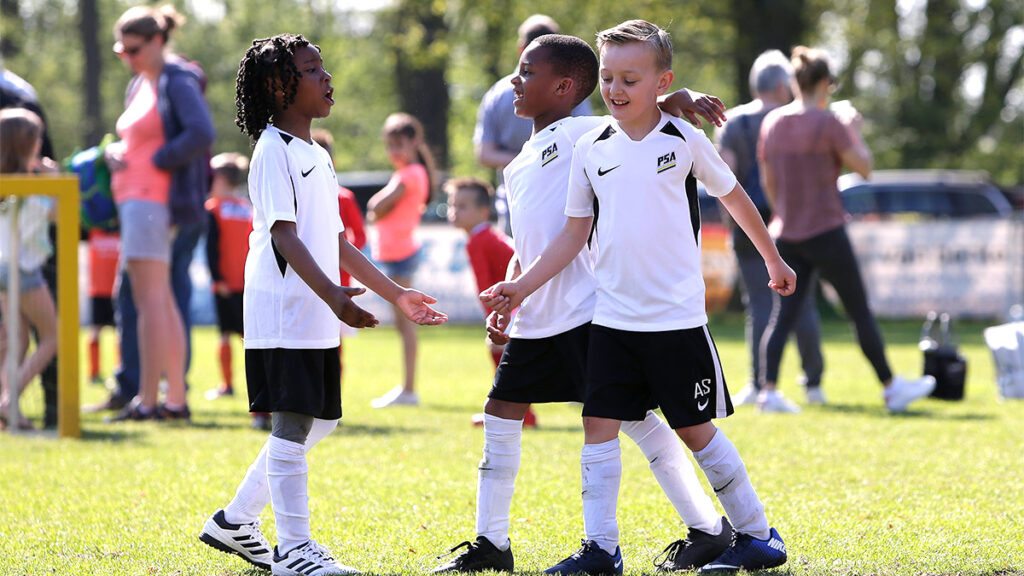 3 youth footballers celebrating after scoring a goal