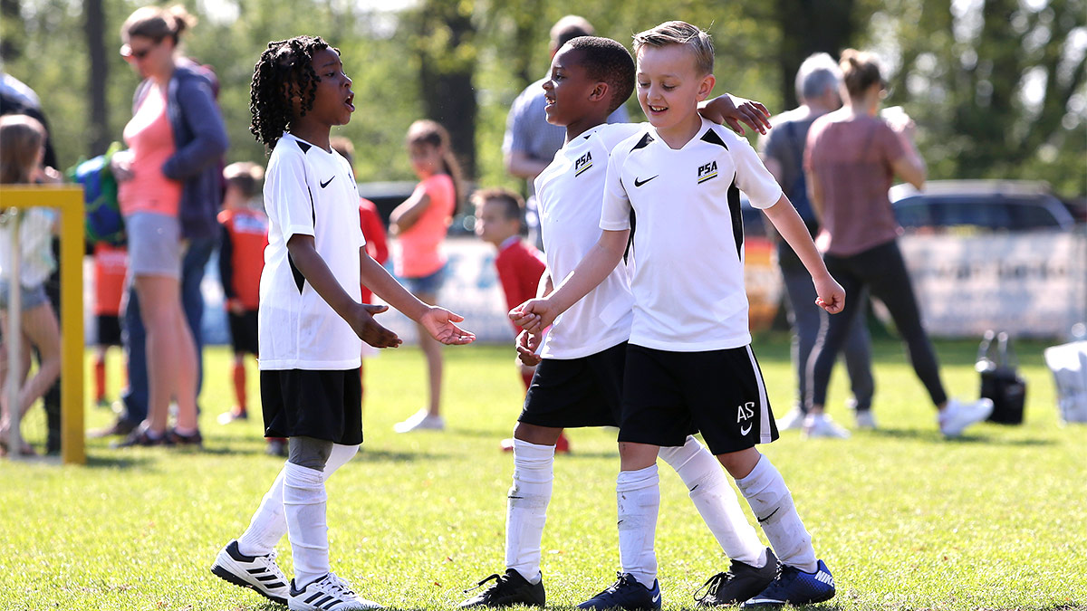 3 youth footballers celebrating after scoring a goal