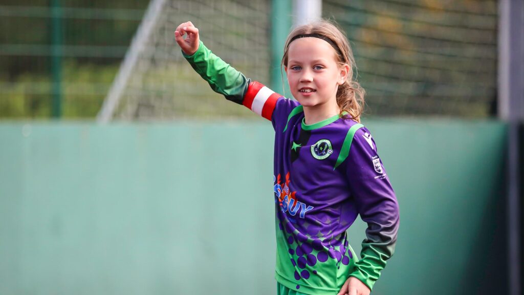 A young female footballer points up field to a team member