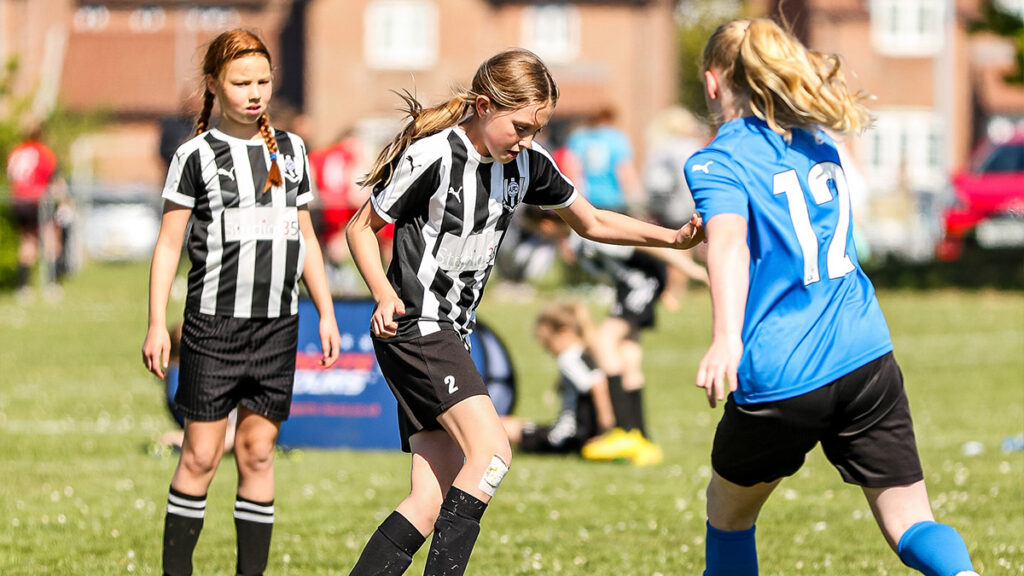 Young girl footballer challenges another player