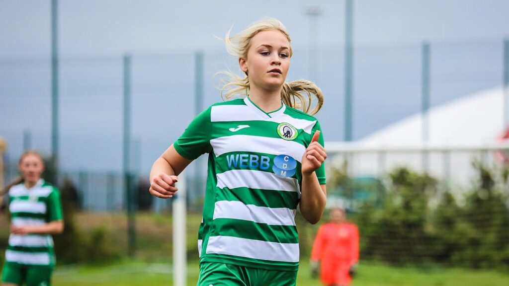 A young girl football player running towards the ball