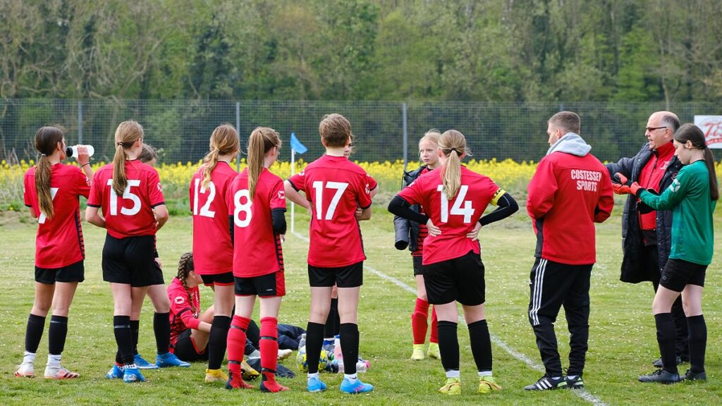 A youth girls football team discussing tactics before starting their next match