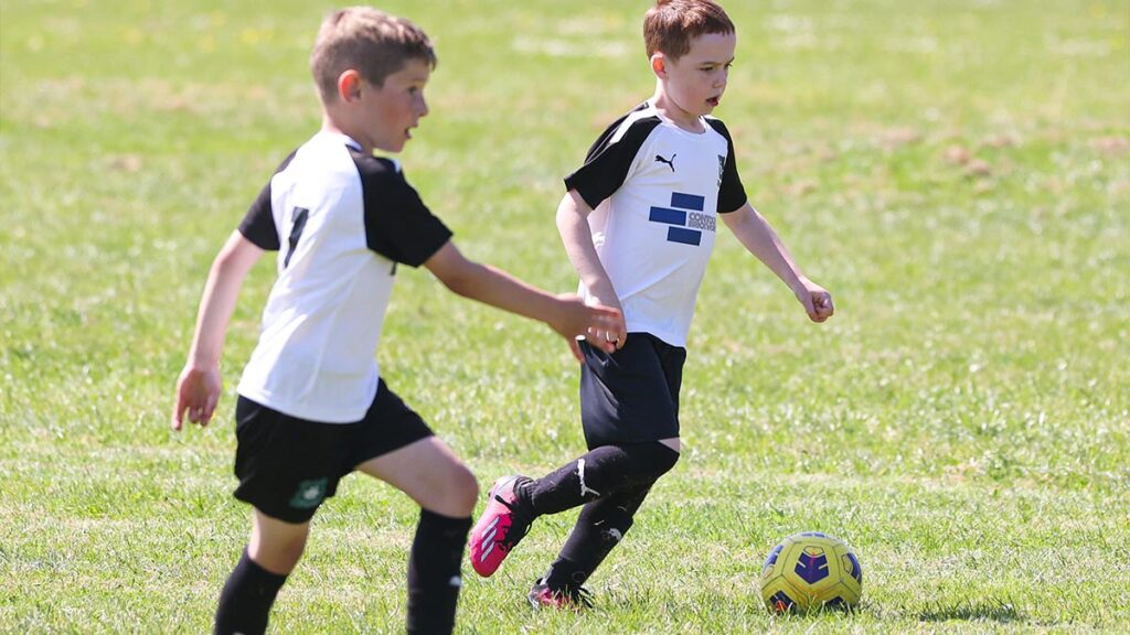 Two young footballers push up field with possession of the ball