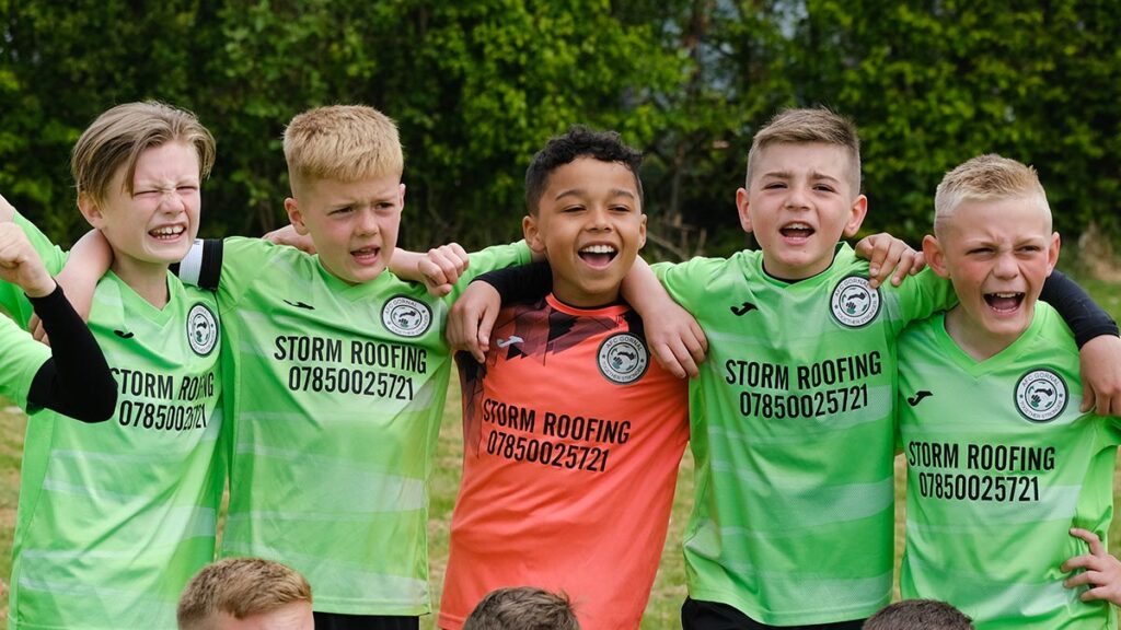 A young team of footballers chanting and cheering to amp up before a match