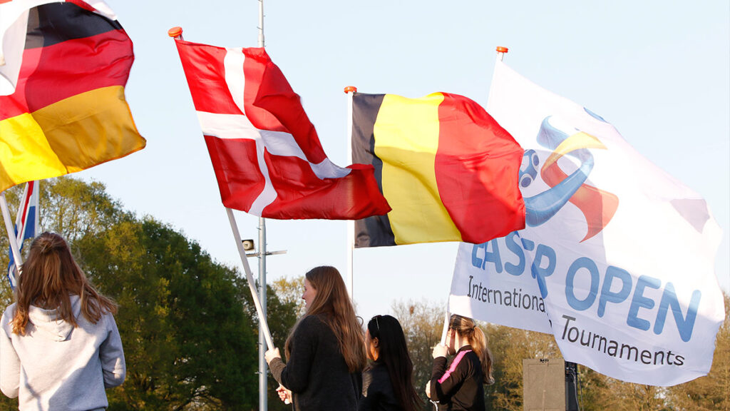 Players holding flags from their country at the open ceremony of the Easter Open Football Tournament