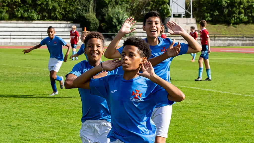 A team of young boys celebrating after scoring a goal in a football tournament
