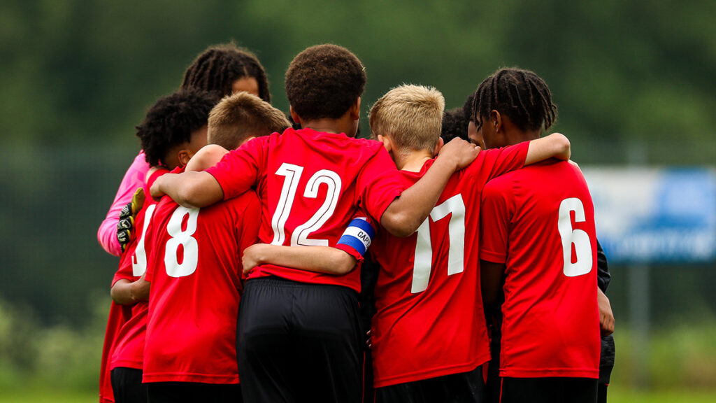 A young football team huddle to discuss tactics before a match