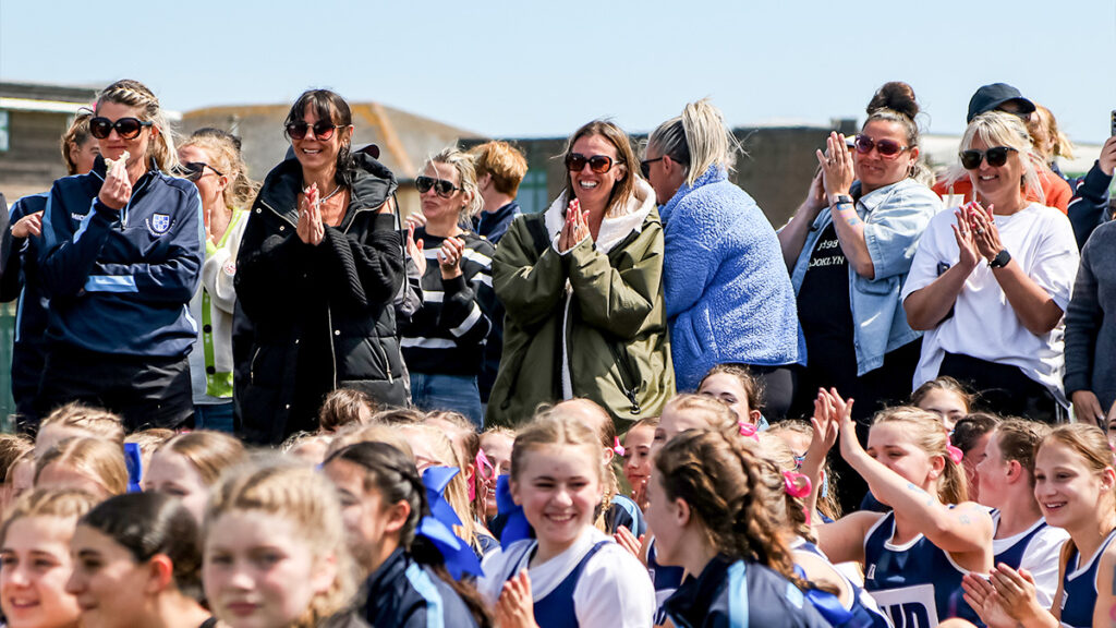 A very happy and excited crowd of netball players and parents at an award ceremony after a tournament