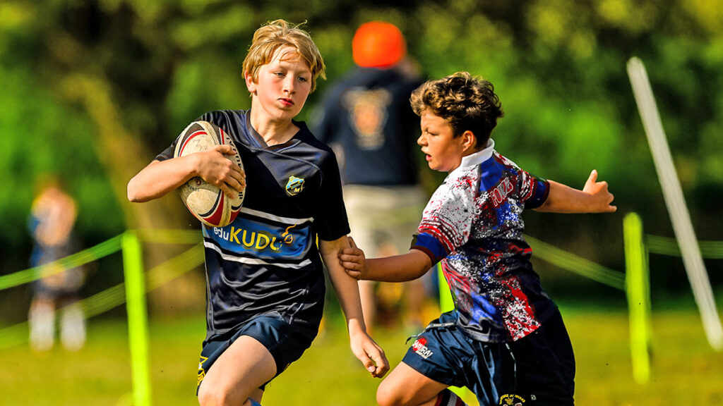 A young rugby player narrowly escapes a challenge