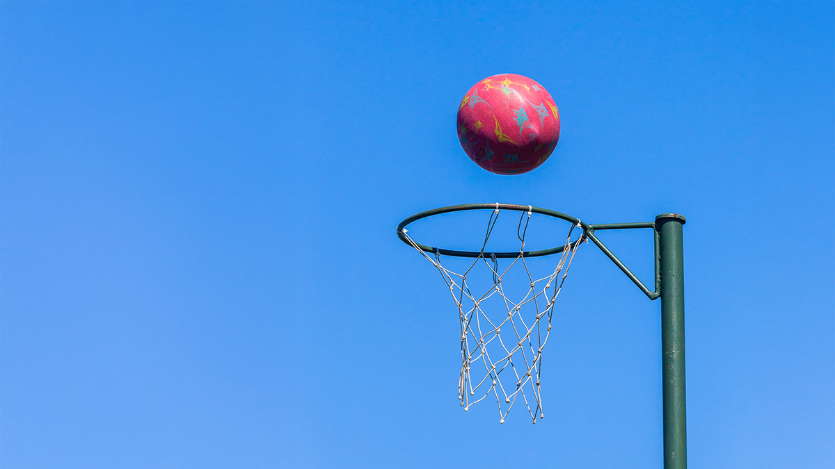 A netball in the air heading towards the net
