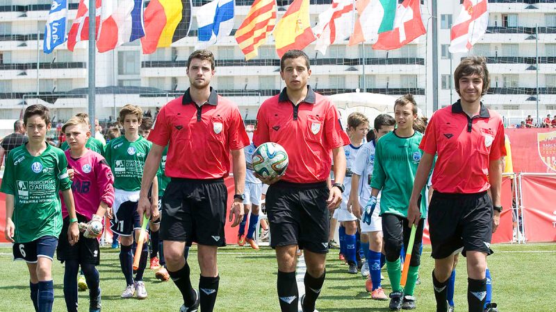 Referees taking the ball onto the pitch for a match at the Barcelona Football Festival