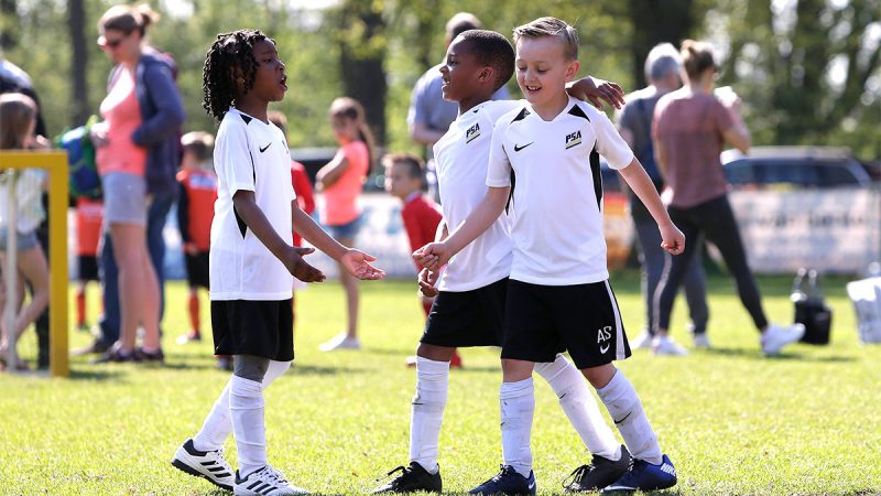 3 youth footballers celebrating after scoring a goal