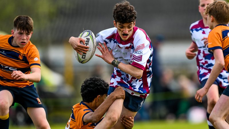 Young rugby player being tackled while pushing the ball up field