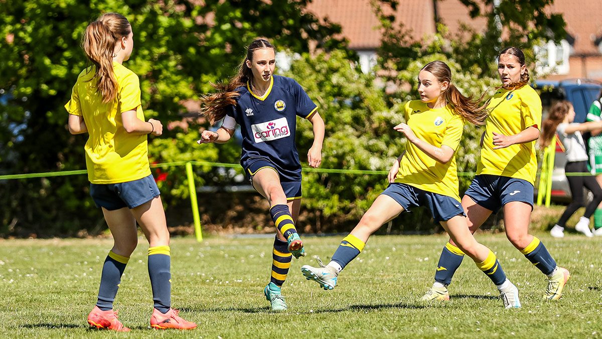 Two young girls football teams contesting the ball