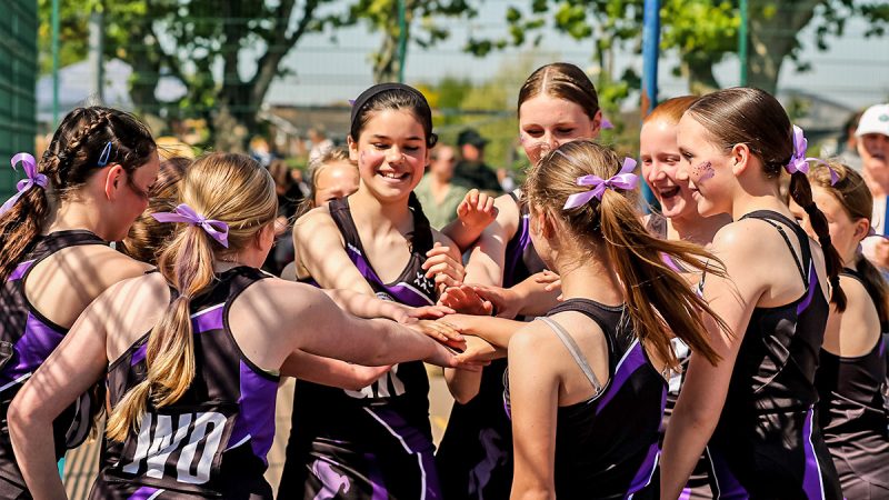 A young netball team laughing while discussing tactics