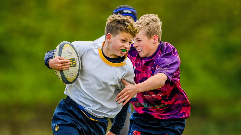 Two young rugby players challenging for possession of the ball