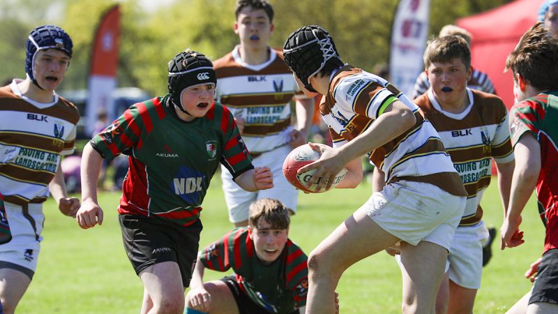 A young rugby player is faced with the opposition as he heads up field