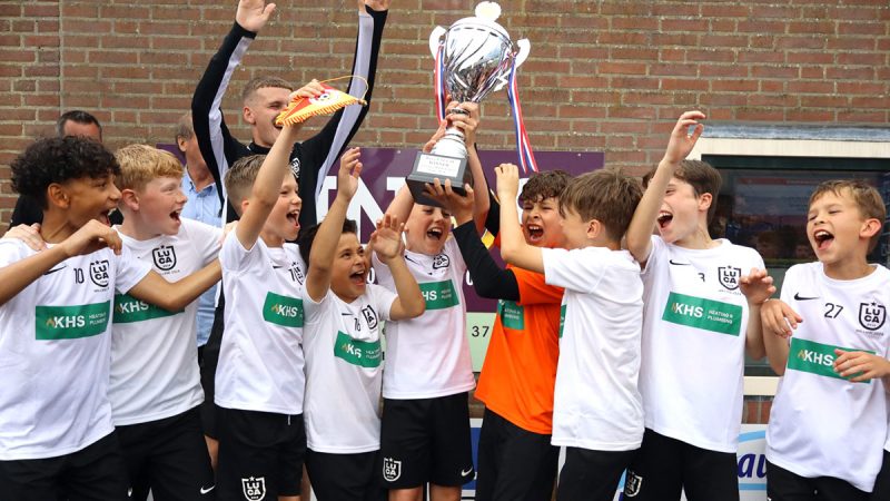 A young team of footballers lifting their trophy in the air while cheering
