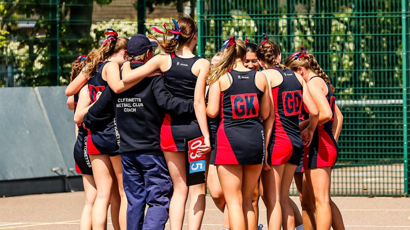 A young netball team huddle in celebration