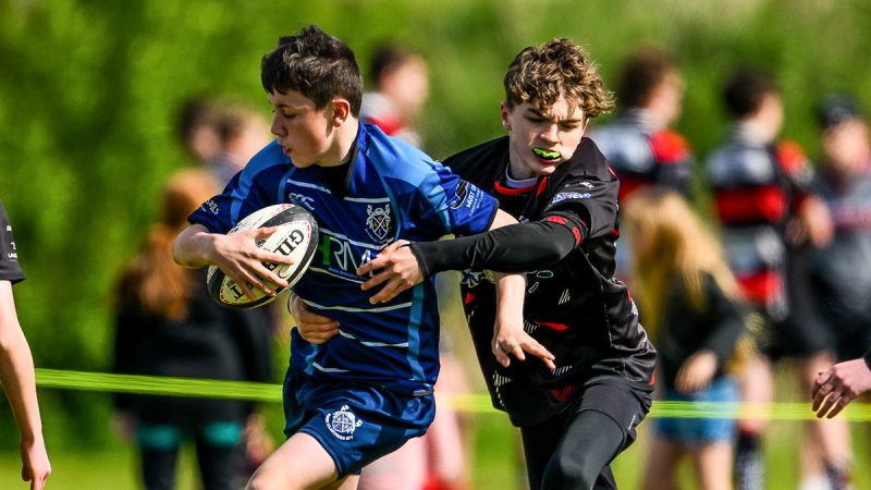 A young rugby player gets the ball past the opposition