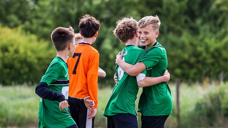 Two young footballers hug in celebration