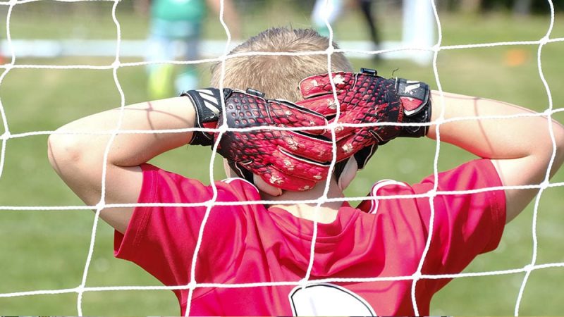 Young football goalie, resting while watching play up the field at the Sports Tours West Sussex Football Tournament